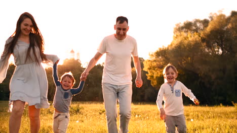 Happy-family-their-man-with-two-children-walking-on-the-field-at-sunset-in-the-sunset-light-in-the-summer-in-warm-weather.